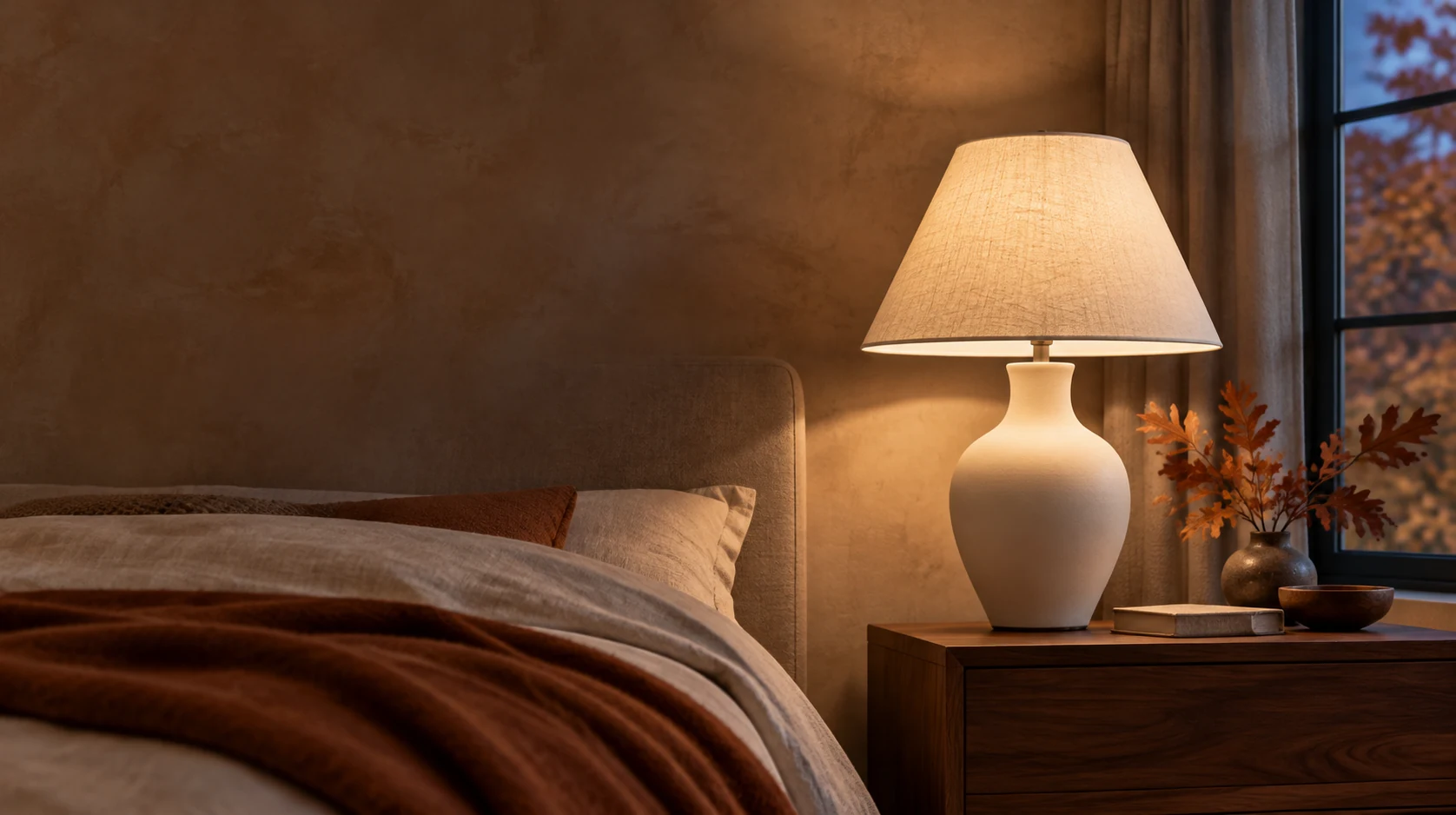 Eine leuchtende Nachttischlampe in einem Schlafzimmer mit warmen Herbstt&ouml;nen.